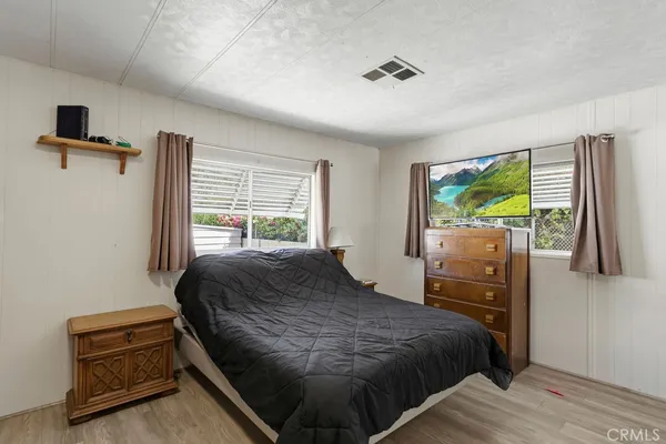 a bedroom with a bed and a flat tv screen on dresser