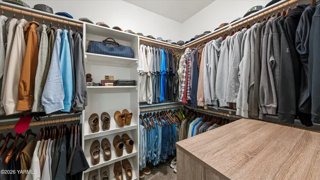 a view of walk in closet with clothes and shoes