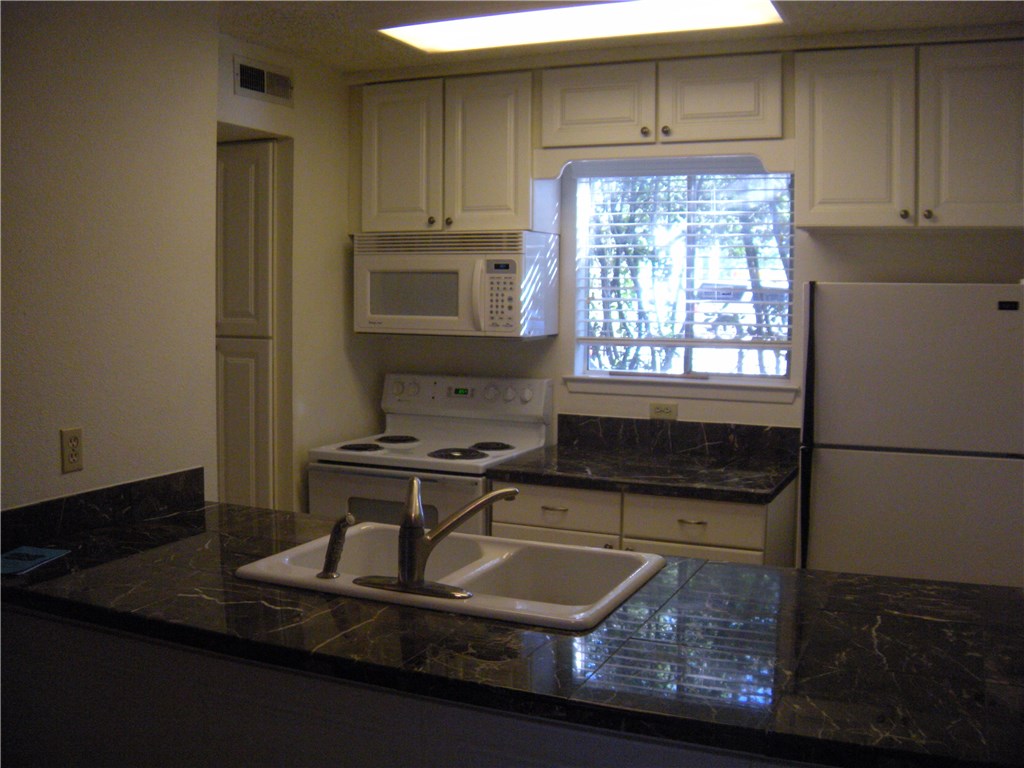 6910 Hart Lane, Unit 502 Austin, TX 78731 - Photo 9 of 16 a kitchen with kitchen island granite countertop a sink stove and cabinets