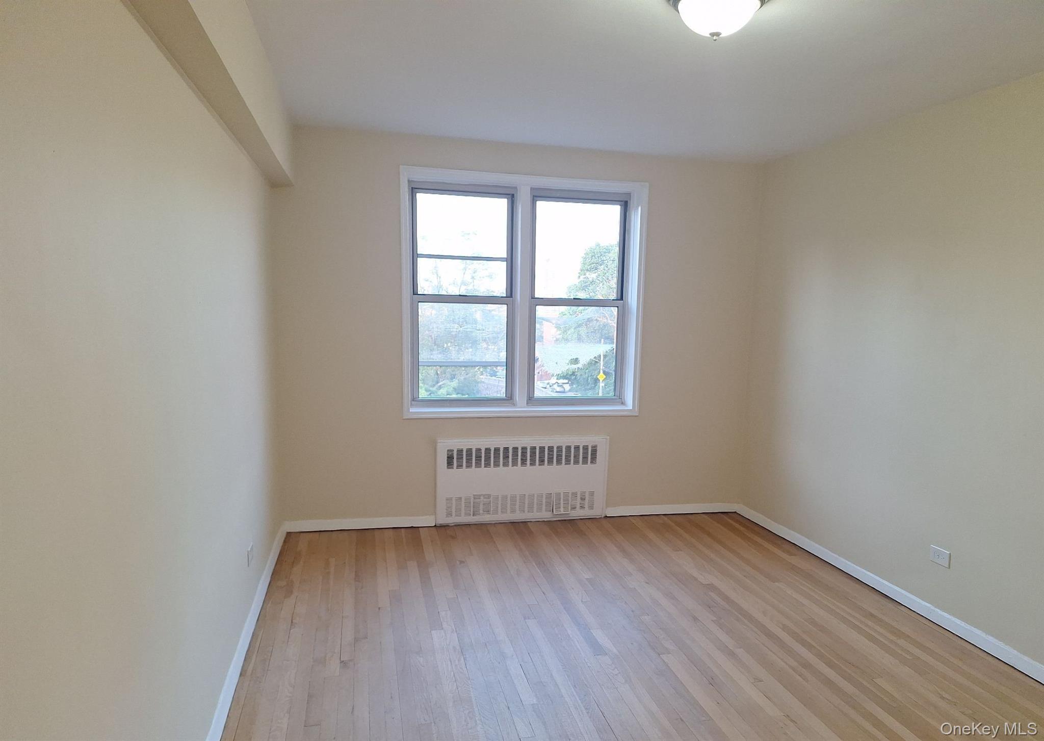 3475 Greystone Avenue, Unit 7E Bronx, NY 10463 - Photo 4 of 12 an empty room with wooden floor and windows