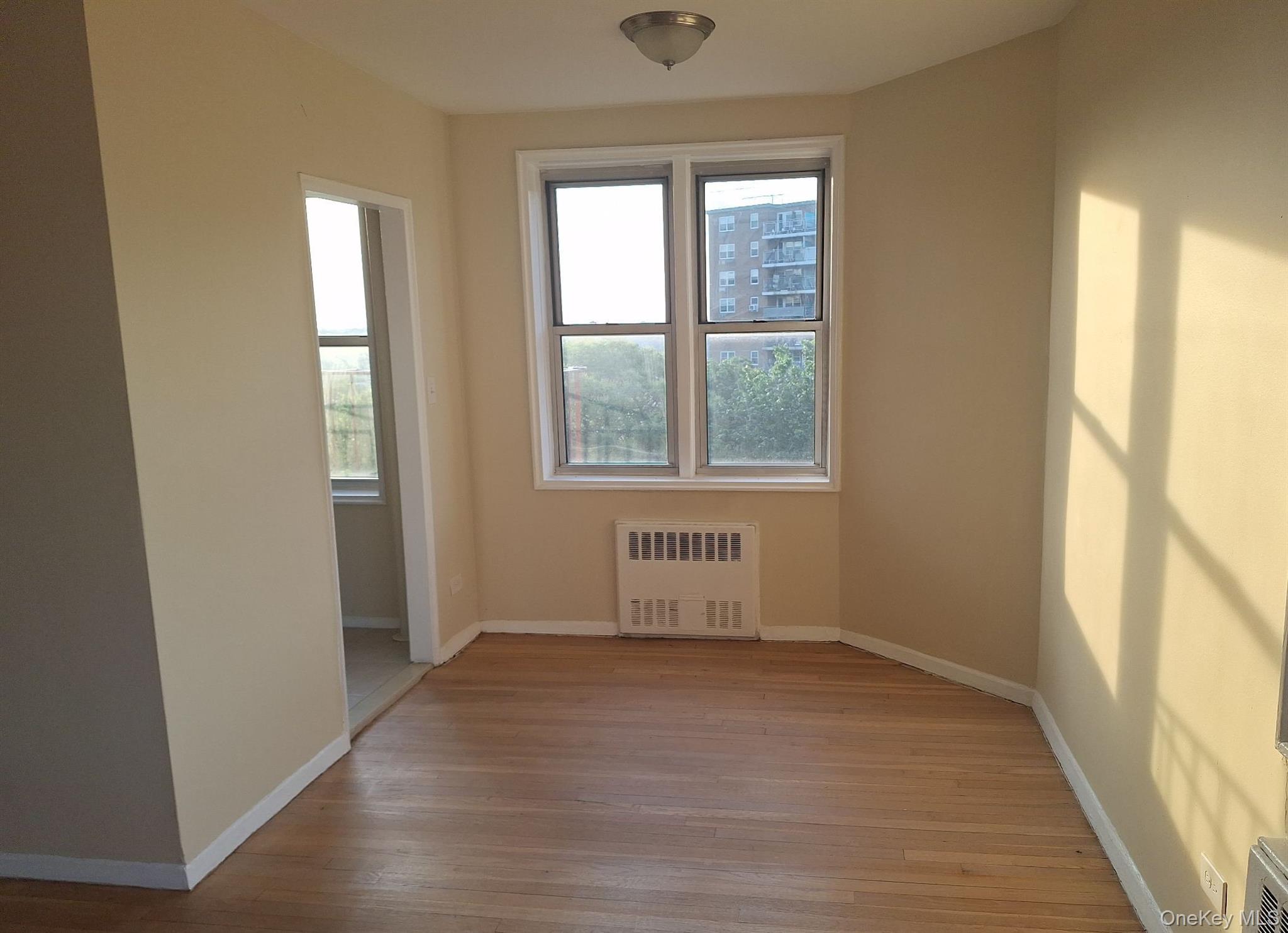 3475 Greystone Avenue, Unit 7E Bronx, NY 10463 - Photo 8 of 12 an empty room with wooden floor and windows