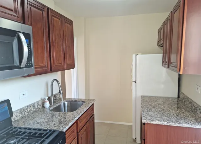 a kitchen with granite countertop a sink a stove and a refrigerator with wooden cabinets