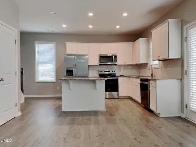 a kitchen with kitchen island white cabinets and stainless steel appliances