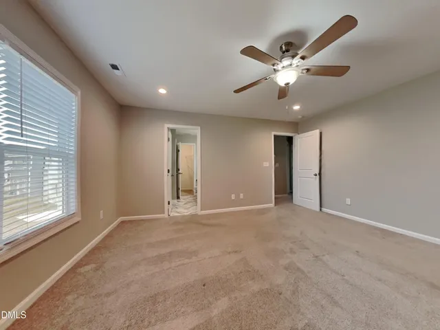 a view of an empty room with a ceiling fan and window