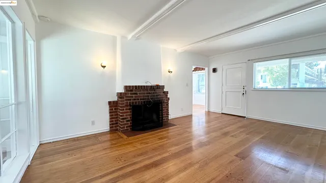 an empty room with wooden floor staircase and windows