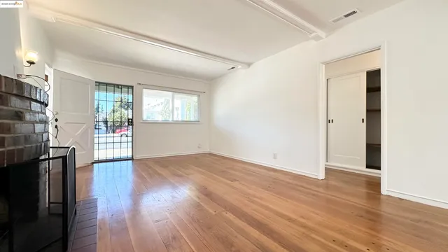 an empty room with wooden floor and a kitchen