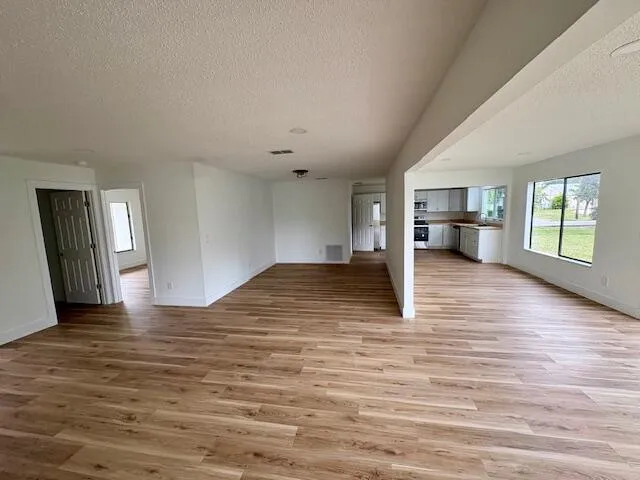 a view of empty room with kitchen and window