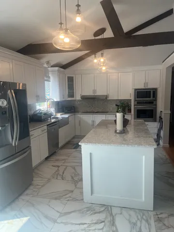 a kitchen with kitchen island a sink stainless steel appliances and window
