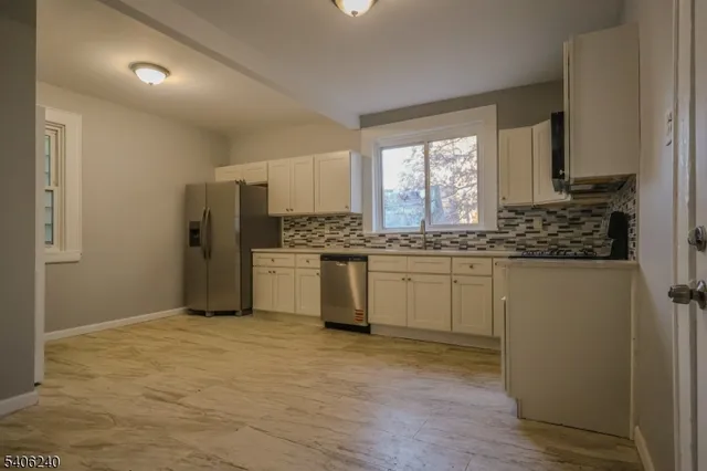 a kitchen with white cabinets and window