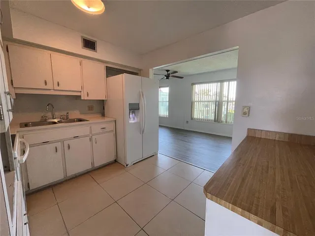 a view of a kitchen with wooden floor a ceiling fan and windows