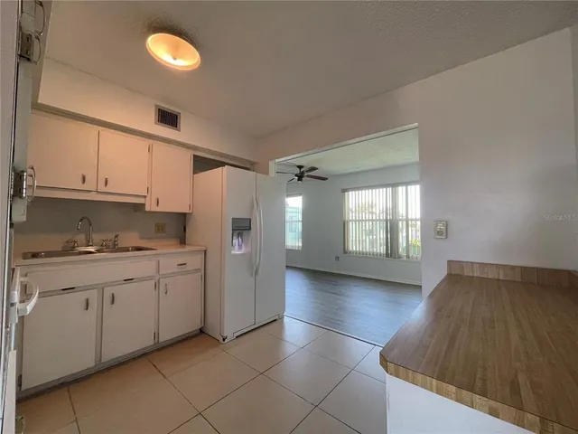 a view of a kitchen with a sink a ceiling fan and wooden floor