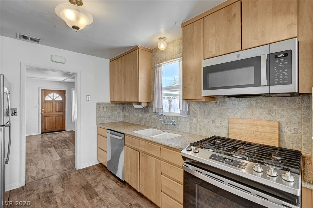 629 L Avenue Boulder City, NV 89005 - Photo 15 of 46 Kitchen featuring light wood finish cabinets, stainless steel appliances, decorative backsplash, and light stone countertops