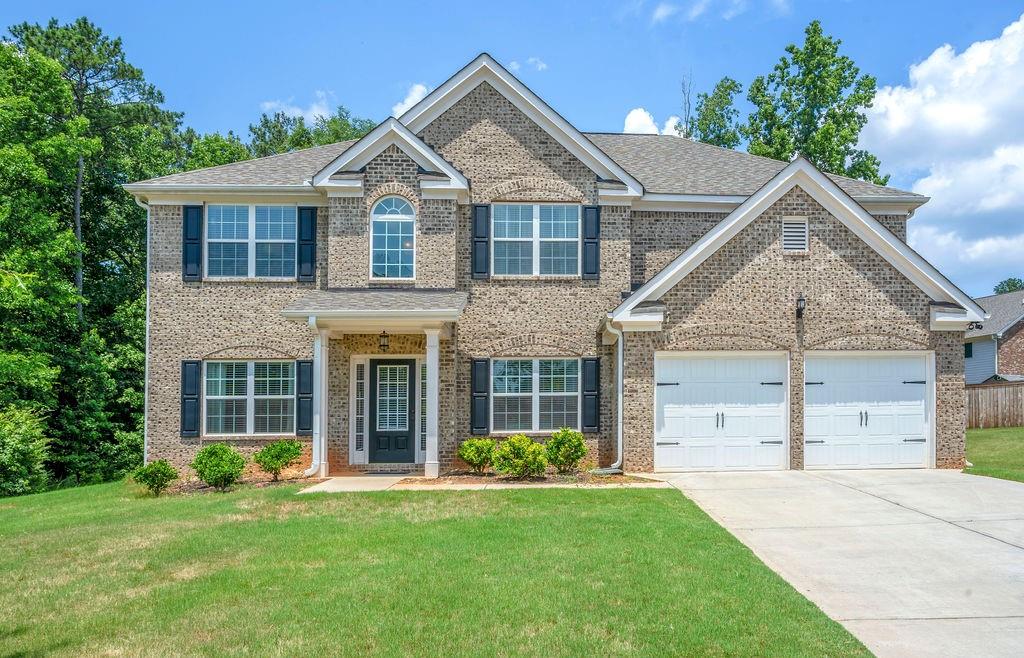 a view of a yard in front of a house with plants and large tree