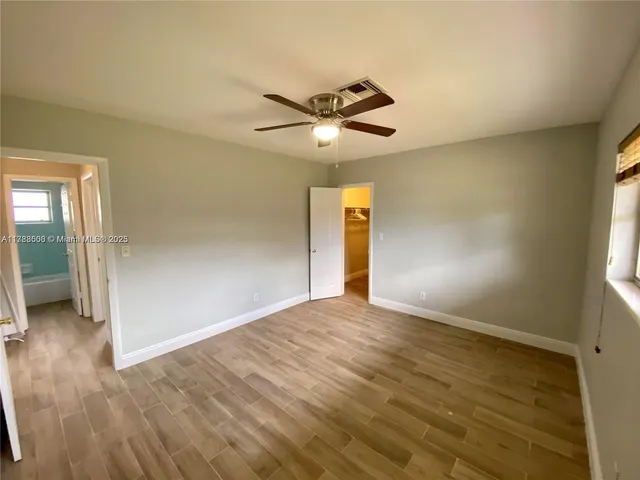 a view of empty room with wooden floor and fan