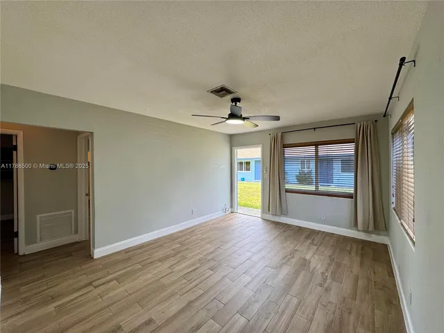 a view of an empty room with a window and wooden floor