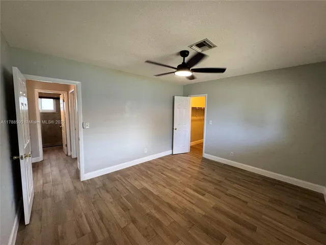 a view of empty room with wooden floor and fan