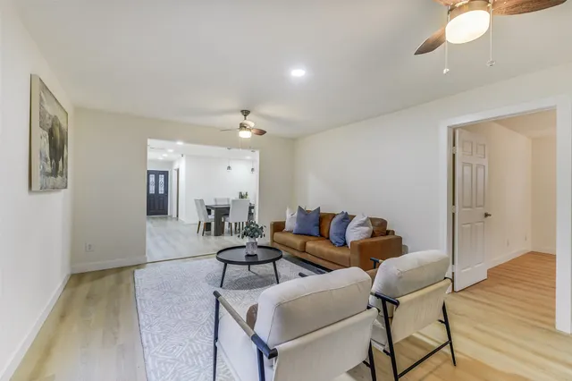 a living room with couches and kitchen view with wooden floor