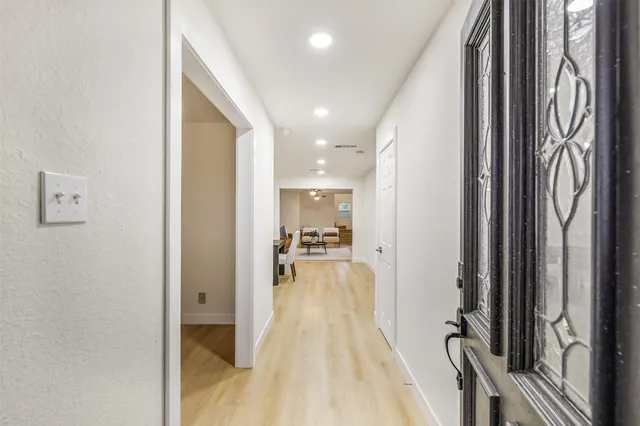 a view of a hallway with wooden floor and a bathroom