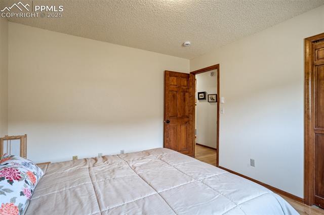 4385 Sandstone Road Monument, CO 80132 - Photo 27 of 50 Bedroom featuring light wood-style floors and a textured ceiling