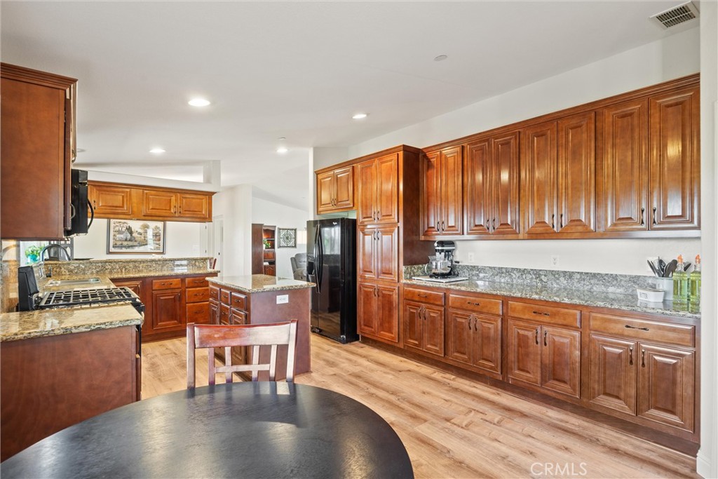19350 Timbercove Drive Corning, CA 96021 - Photo 16 of 60 a kitchen with stainless steel appliances granite countertop a stove top oven a dining table and chairs with wooden floor