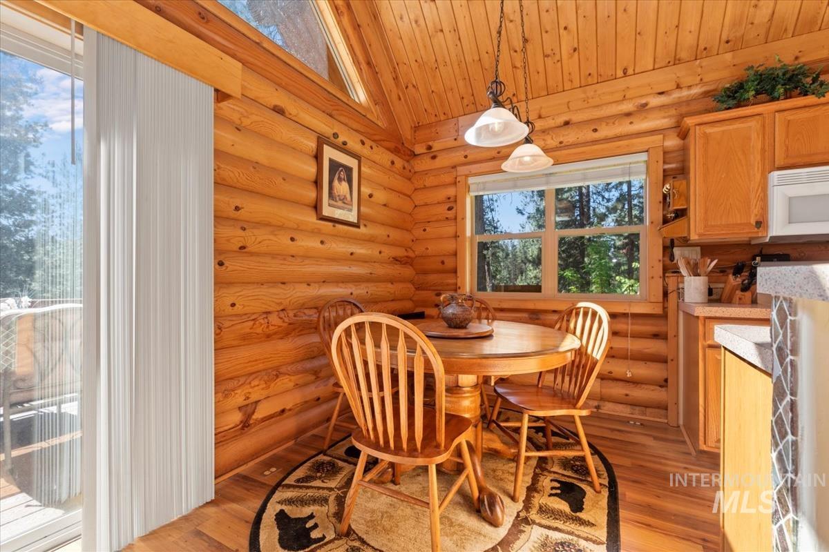 10 Elk Point Road Garden Valley, ID 83622 - Photo 13 of 42 Dining space with rustic walls, light wood-style floors, and vaulted ceiling