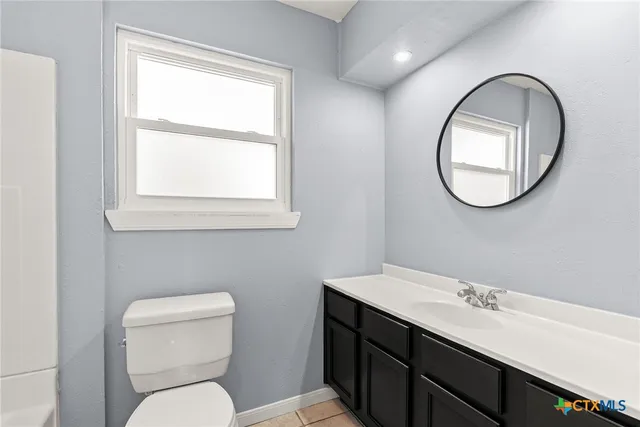 a bathroom with a toilet a sink and mirror