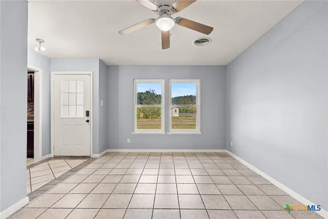 a view of an empty room and window and chandelier fan