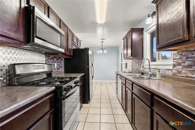 a kitchen with stainless steel appliances granite countertop a stove a sink and a microwave