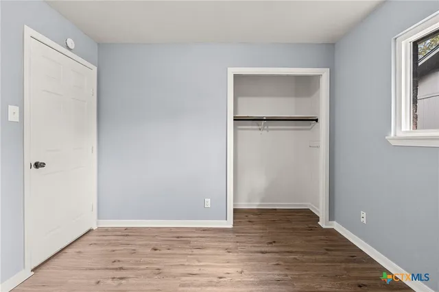 a view of an empty room with closet and a window
