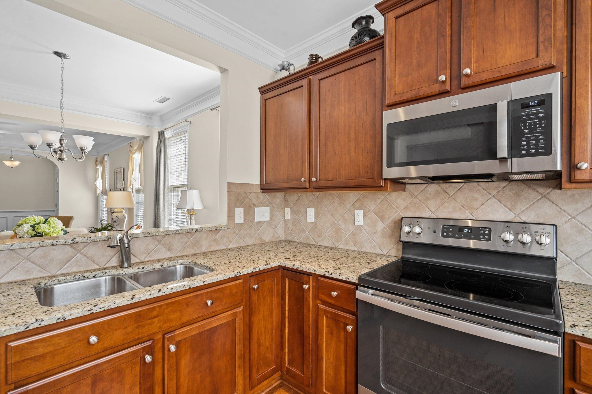 10109 Falls Meadow Court Raleigh, NC 27617 - Photo 13 of 37 a kitchen with granite countertop a stove top oven microwave and cabinets