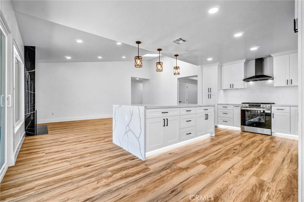 17472 Bellport Circle Huntington Beach, CA 92649 - Photo 4 of 23 a large white kitchen with granite countertop a stove top oven a sink and white cabinets with wooden floor
