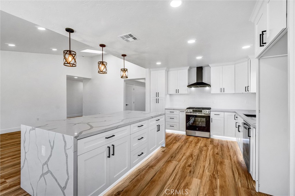 17472 Bellport Circle Huntington Beach, CA 92649 - Photo 5 of 23 a open kitchen with kitchen island a stove a sink dishwasher and a refrigerator with wooden floor