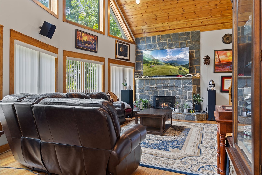 332 Two Rivers Drive Westminster, SC 29693 - Photo 27 of 50 A striking stone fireplace anchors this living space, offering warmth beneath a vaulted wood-paneled ceiling and abundant natural light.