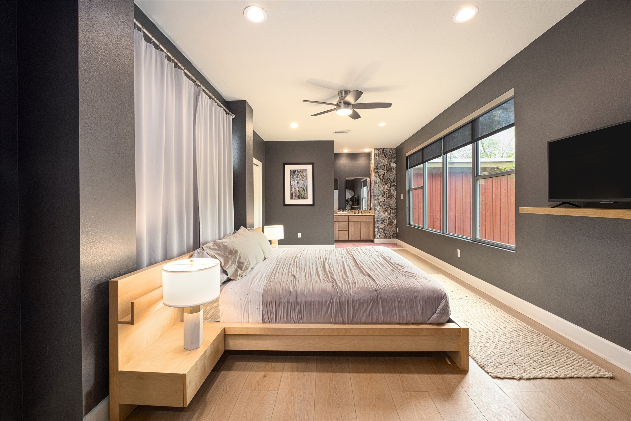 2302 East 9th Street Austin, TX 78702 - Photo 16 of 31 Recessed lighting illuminates this contemporary bedroom, boasting hardwood flooring and a stylish ceiling fan for comfort.