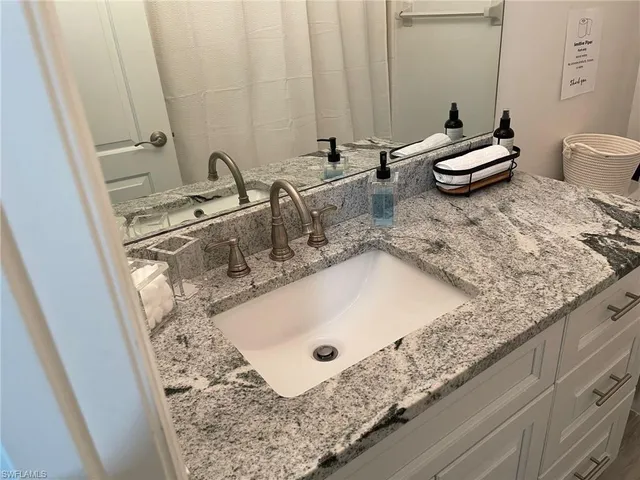 a bathroom with a granite countertop sink a toilet and a mirror