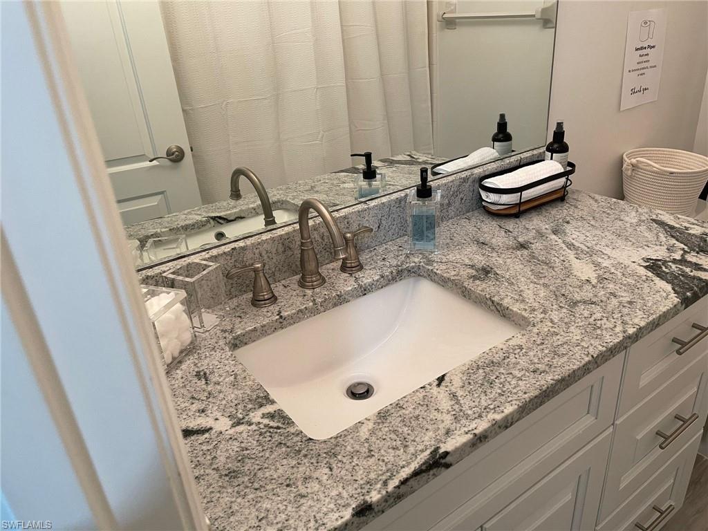 136 Harrison Road, Unit L3 Naples, FL 34112 - Photo 15 of 31 a bathroom with a granite countertop sink and a mirror