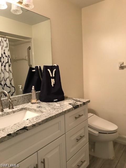 136 Harrison Road, Unit L3 Naples, FL 34112 - Photo 16 of 31 a bathroom with a granite countertop sink a toilet and a mirror