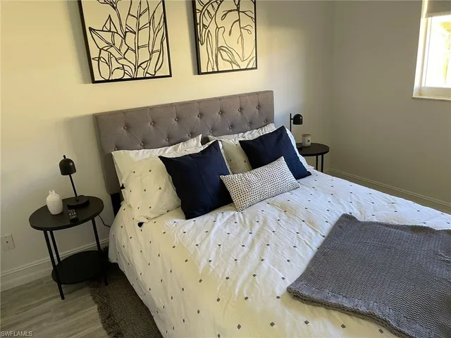 a bed sitting in a bedroom next to a wall with a painting on the wall