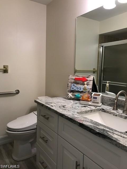 136 Harrison Road, Unit L3 Naples, FL 34112 - Photo 21 of 31 a bathroom with a granite countertop toilet sink and mirror