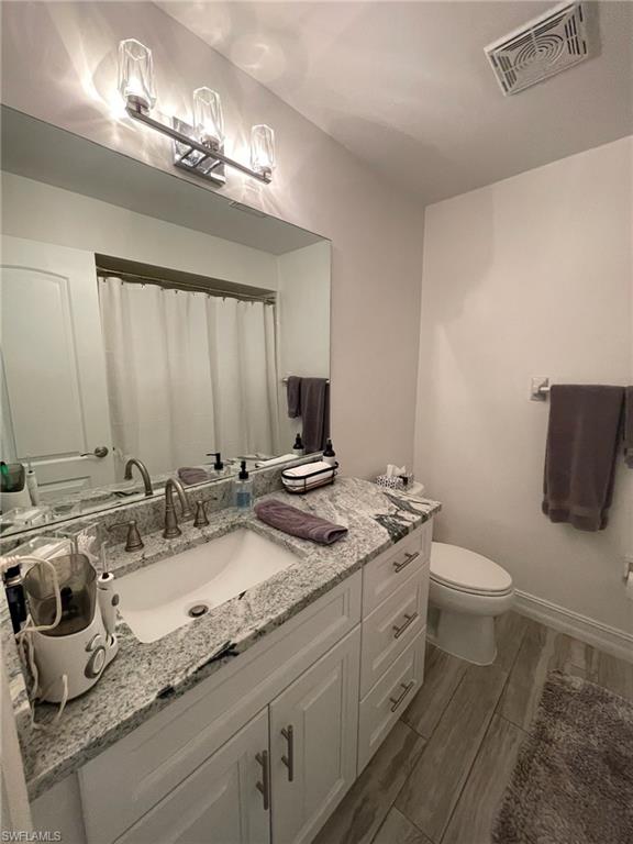136 Harrison Road, Unit L3 Naples, FL 34112 - Photo 29 of 31 a bathroom with a granite countertop sink a toilet and a mirror