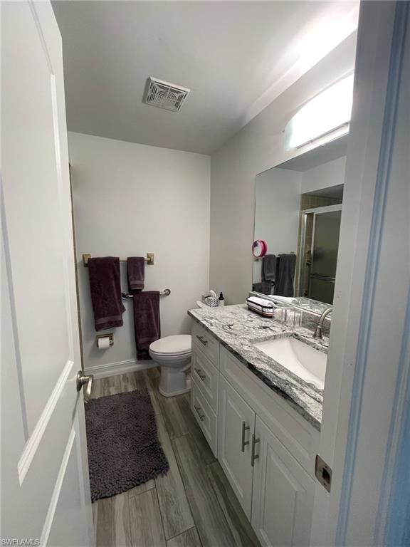 136 Harrison Road, Unit L3 Naples, FL 34112 - Photo 30 of 31 a bathroom with a granite countertop toilet sink and mirror
