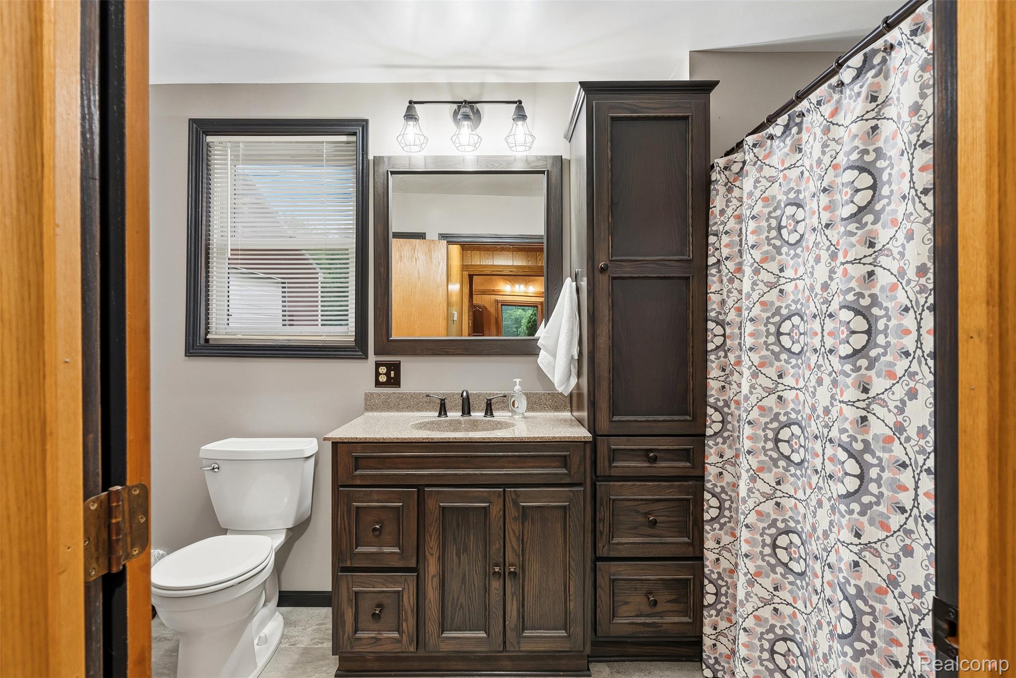 6109 North State Road Davison, MI 48423 - Photo 24 of 39 Bathroom vanity with integrated sink, stone-finish countertop, and dark wood-finish cabinetry