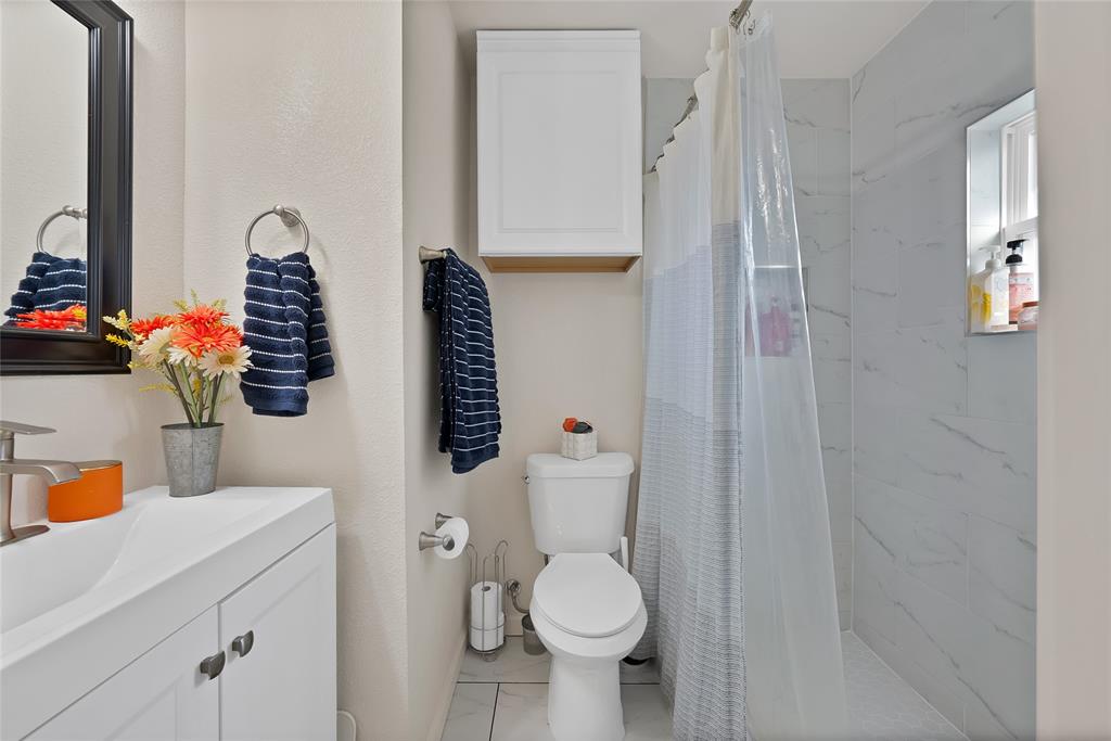 604 Moore Street Garland, TX 75040 - Photo 17 of 26 a bathroom with a toilet sink and mirror