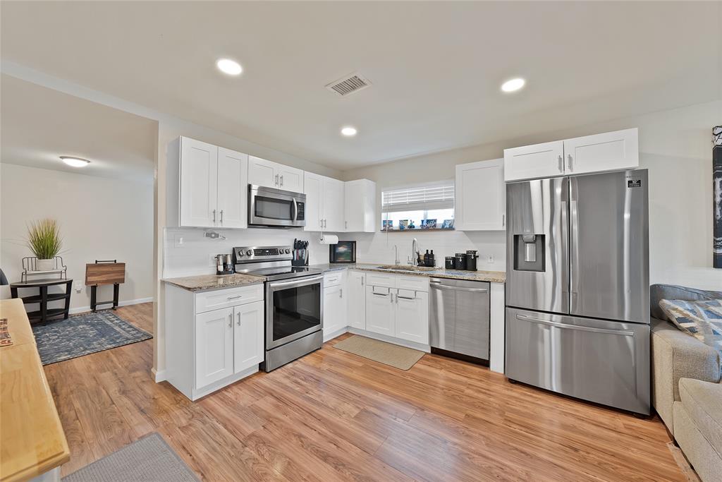 604 Moore Street Garland, TX 75040 - Photo 5 of 26 a kitchen with granite countertop a refrigerator stove and wooden floors