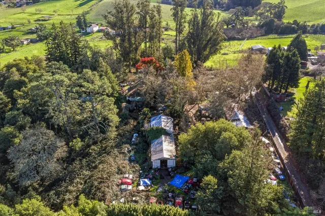 a view of a white house next to a road and yard