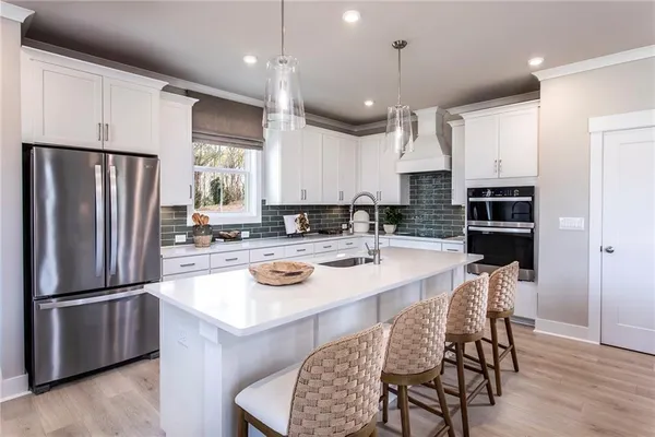 a kitchen with stainless steel appliances granite countertop a refrigerator a stove a sink a dining table and chairs