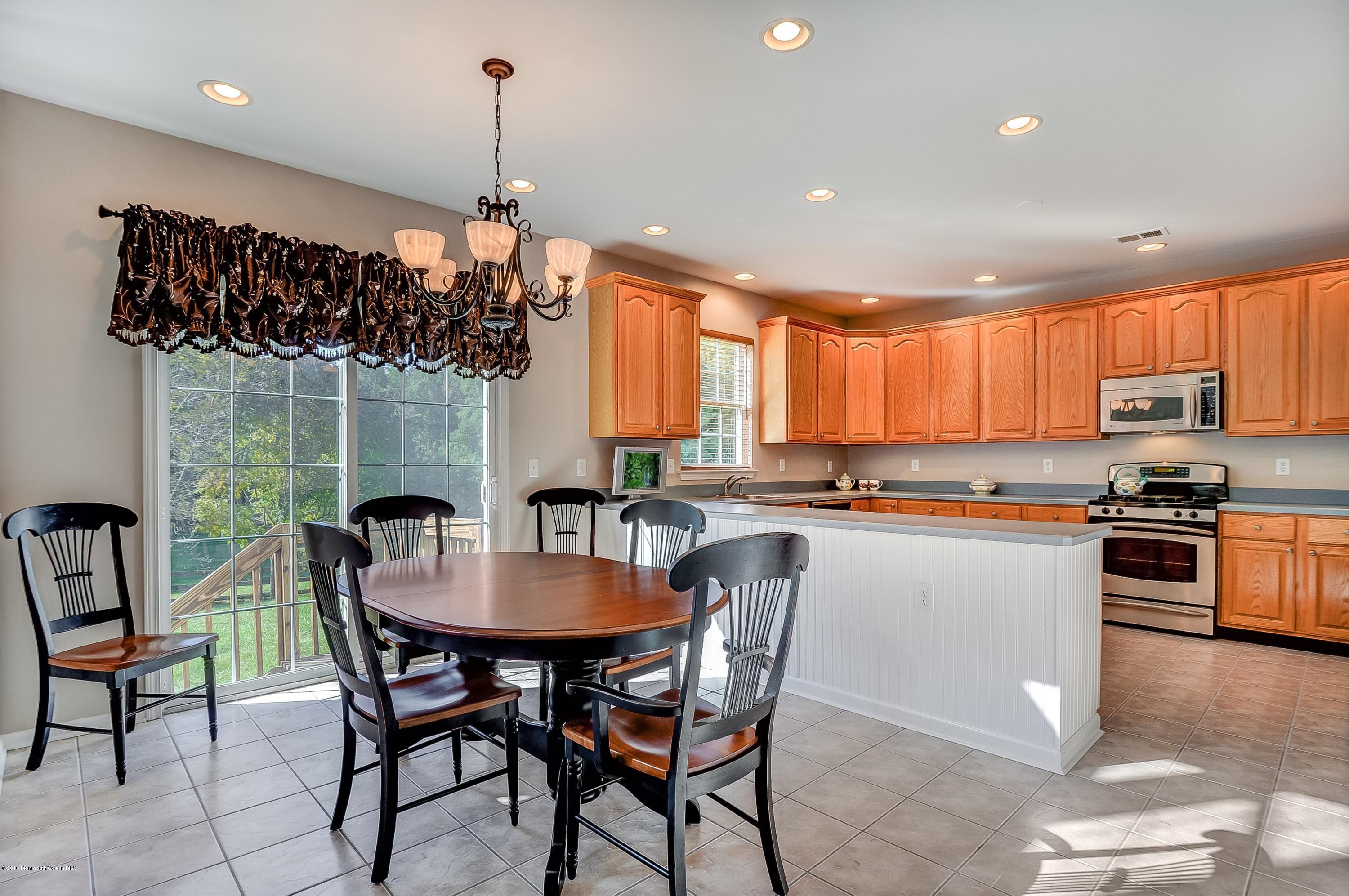 323 Wedgewood Road Morganville, NJ 07751 - Photo 10 of 27 a kitchen with a dining table chairs stainless steel appliances and cabinets