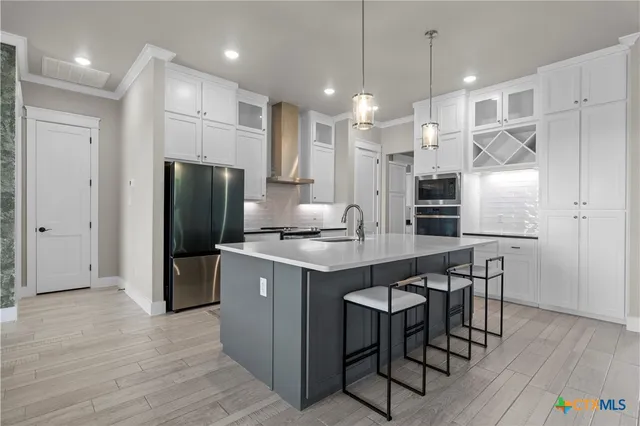 a kitchen with stainless steel appliances kitchen island granite countertop a refrigerator a stove a sink a dining table and chairs with wooden floor