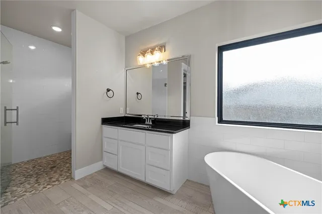 a bathroom with a double vanity sink a mirror and a bathtub