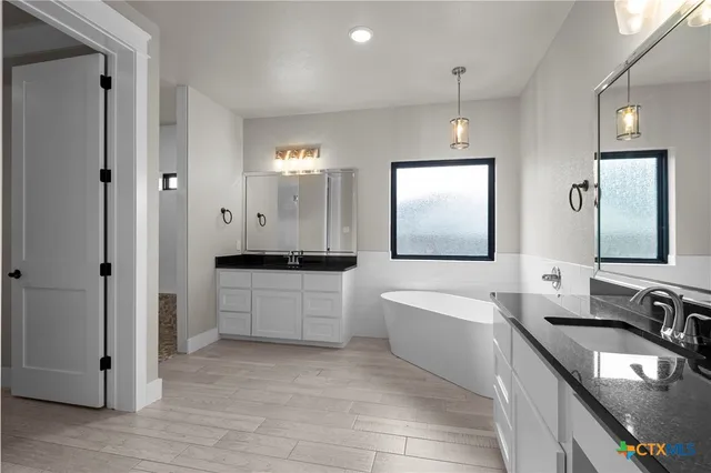 a bathroom with a double vanity sink a bathtub and mirror